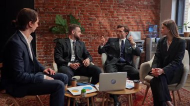 Modern bir ofis ortamında masanın etrafında oturan dört meslektaşı profesyonel bir iş toplantısındalar. Yavaş çekim.