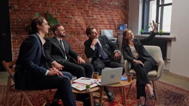 Bir iş ekibi modern ofis ortamında toplantı yapıyor. Ağır çekim. Bir kadın iş arkadaşlarıyla selfie çekiyor. Yavaş çekim.