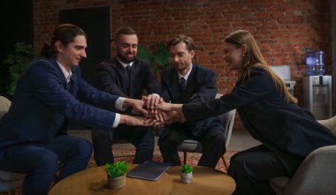 Resmi giyinmiş dört iş adamından oluşan bir grup, birliği simgeleyen bir masanın üzerinde el ele tutuşuyor..
