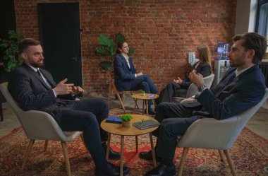 Bir grup profesyonel tuğla duvarlı modern ofis ortamında ciddi bir tartışma yapıyorlar..