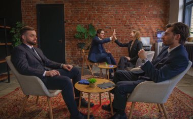 İş kıyafeti giymiş profesyonellerden oluşan bir ekip modern bir ofis ortamında, takım çalışması ve işbirliği sergileyerek tartışmalara girdi..