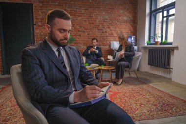 Bir grup profesyonel, tuğla duvar ve zarif mobilyaların yer aldığı çağdaş bir ofis içinde bir iş toplantısına katıldı..