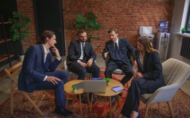 Çağdaş bir ofiste dizüstü bilgisayardaki verileri analiz eden bir grup profesyonel iş toplantısına katıldı..