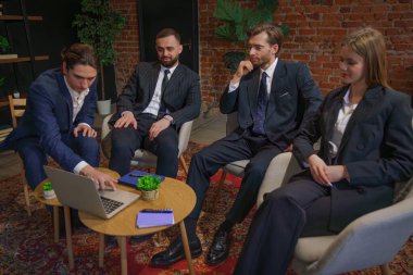 Çağdaş bir ofiste dizüstü bilgisayardaki verileri analiz eden bir grup profesyonel iş toplantısına katıldı..