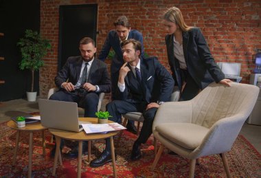 Çağdaş bir ofiste dizüstü bilgisayardaki verileri analiz eden bir grup profesyonel iş toplantısına katıldı..