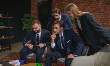 Çağdaş bir ofiste dizüstü bilgisayardaki verileri analiz eden bir grup profesyonel iş toplantısına katıldı..