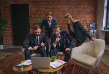 Çağdaş bir ofiste dizüstü bilgisayardaki verileri analiz eden bir grup profesyonel iş toplantısına katıldı..