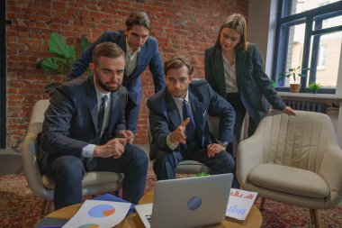 Çağdaş bir ofiste dizüstü bilgisayardaki verileri analiz eden bir grup profesyonel iş toplantısına katıldı..