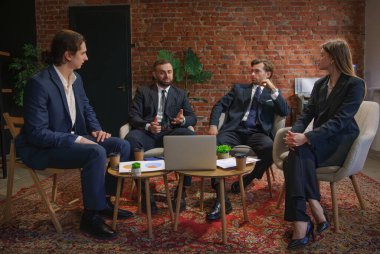 Çağdaş bir ofiste dizüstü bilgisayardaki verileri analiz eden bir grup profesyonel iş toplantısına katıldı..