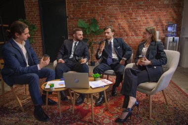 Çağdaş bir ofiste dizüstü bilgisayardaki verileri analiz eden bir grup profesyonel iş toplantısına katıldı..