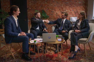 Çağdaş bir ofiste dizüstü bilgisayardaki verileri analiz eden bir grup profesyonel iş toplantısına katıldı..