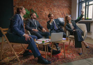 Bir iş ekibi modern ofis ortamında toplantı yapıyor. Bir kadın iş arkadaşlarıyla selfie çekiyor..