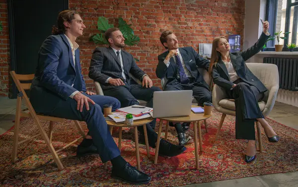 Bir iş ekibi modern ofis ortamında toplantı yapıyor. Bir kadın iş arkadaşlarıyla selfie çekiyor..