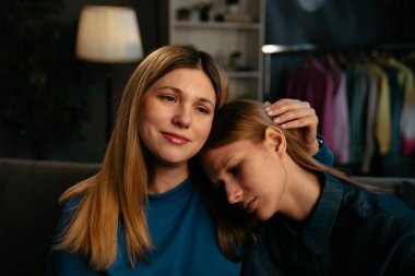 Bir anne kızını rahatlatırken, rahat bir koltukta otururken duygusal destek sağlarken görülüyor..