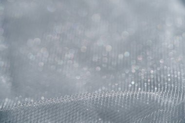 Bir fotoğraf, köpüklü su damlacıklarıyla süslenmiş karmaşık ağ kumaş desenlerini yakalar. Makro