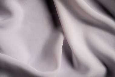 Zarif bir şekilde katlanmış beyaz kumaş görüntüsü, pürüzsüz ve ipeksi bir doku sergiliyor, tasarım ilhamı için mükemmel. Makro