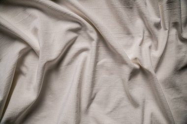 Yumuşak beyaz kumaş manzarası, nazik kıvrımlarını ve ince dokusunu sergiliyor, zarafet ve sadelik hissi yaratıyor. Makro