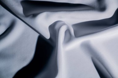 Bu resim beyaz ve gri tonlarında yumuşak bir kumaşın akış dokusunu yakalar ve zarafet hissi uyandırır. Makro