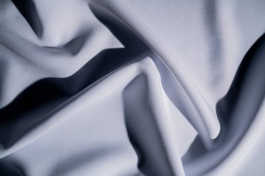 Bu resim beyaz ve gri tonlarında yumuşak bir kumaşın akış dokusunu yakalar ve zarafet hissi uyandırır. Makro