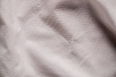 Yumuşak beyaz kumaş manzarası, hassas kırışıklıklar ve hoş bir görsel şablon oluşturan yapısal detaylar. Makro