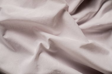 Yumuşak beyaz kumaş manzarası, hassas kırışıklıklar ve hoş bir görsel şablon oluşturan yapısal detaylar. Makro