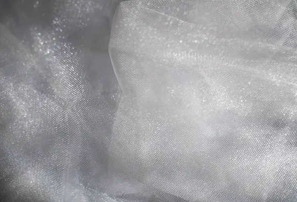 Yumuşak beyaz kumaş manzarası, nazik kıvrımlarını ve ince dokusunu sergiliyor, zarafet ve sadelik hissi yaratıyor. Makro