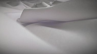 Dokuları ve yumuşak kıvrımları gösteren, karmaşık dokuma detaylarını vurgulayan beyaz bir kumaş. Makro