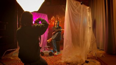 Sahne arkasında. Bir fotoğrafçı sanatsal arkaplanlar arasında canlı ışıklandırma ve aksesuar kullanarak yaratıcı bir portre yakalar..