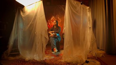 Sahne arkasında. İlginç ışıklandırma efektleri olan bir stüdyoda oturan birinin büyüleyici bir sanat portresi..