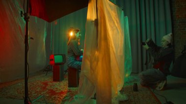 Sahne arkasında. Fotoğrafçı canlı renkli ışıklandırma ve eşsiz kompozisyonlar kullanarak stüdyoda bir model yakalıyor..