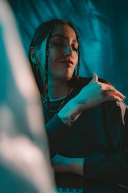 Karamsar bir portre içinde dramatik ışıklandırma, eşsiz bir stil ve düşünceli bir ifade sergileyen bir kişi..