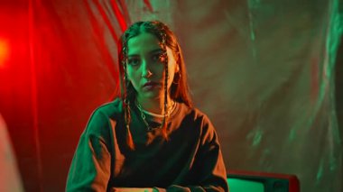 Bir kadın hareketli kırmızı ve yeşil ışıklandırmalı, kasetçalar tutan dengesiz, modası geçmiş bir odada oturuyor. Yavaş çekim