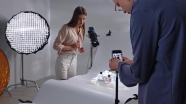 Sahne arkasında. Stüdyoda bir fotoğrafçı stüdyo ışıklandırması ve hassas bir telefon kamerası kullanarak çekim yapar..