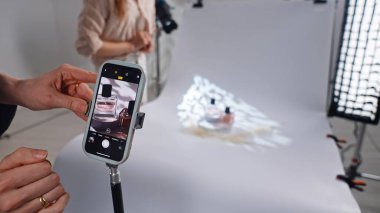 Sahne arkasında. Bir cep telefonu yaratıcı ışık efektleriyle ürün fotoğrafçılığını yakalar. Kurulum basit ve etkili..