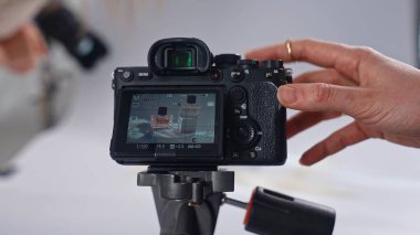 Sahne arkasında. Resim, bir tripodun üzerinde bir ürünü profesyonel bir stüdyoda yakalayan dijital bir kamera tasvir ediyor..