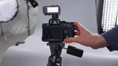 Sahne arkasında. Bir tripodun üzerindeki dijital kamera stüdyo ortamında ürün fotoğrafçılığı için ayarlanıyor..