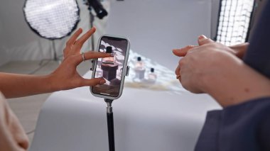 Sahne arkasında. Akıllı telefon kullanarak parfüm şişelerini fotoğraflamak için yaratıcı bir düzenek. Zarif ürün imgeleri sergiliyor..