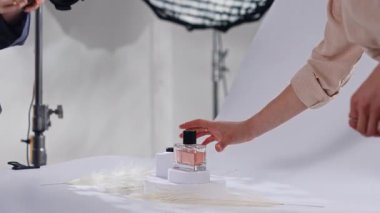 Sahne arkasında. Profesyonel bir fotoğrafçı, bir stüdyo ortamında, ışıklandırma ve kompozisyona odaklanmış parfümlerin sanatsal bir fotoğrafını çekiyor..