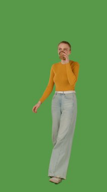 Sarı bluz giyen, elinde fincan tutan, yeşil ekranda yürüyen, krom anahtarı olan biri. Yarım dönüş görünümü