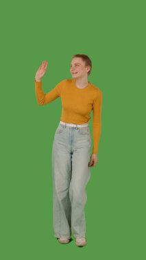 Sarı kazaklı ve geniş paçalı kotlu biri yeşil ekranda yürüyor..