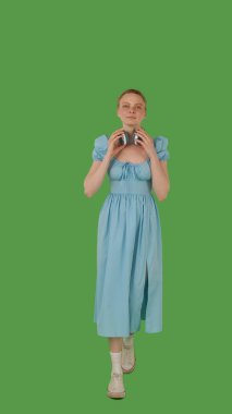 Yürümekten hoşlanan, kulaklık takan, kot mavisi elbise giyen, canlı yeşil ekran, krom anahtara dayanan bir kişi..