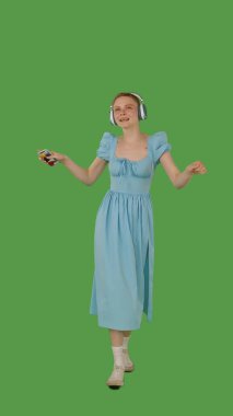 Yürümekten hoşlanan, kulaklık takan, kot mavisi elbise giyen, canlı yeşil ekran, krom anahtara dayanan bir kişi.