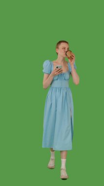 Bir insan yürür ve bir elinde akıllı telefon, diğer elinde bir bardak, yeşil ekranda krom anahtar kullanır..