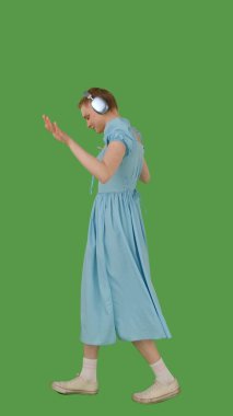 Yürürken müziği seven, kulaklık takan, kot mavisi elbise giyen, canlı yeşil ekran, krom anahtara dayanan bir insan. Yan görünüm