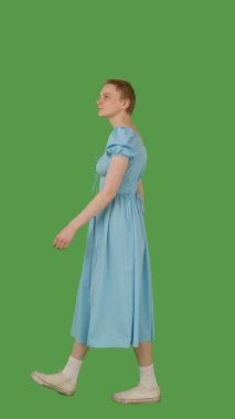 Mavi elbiseli biri yeşil ekranda yürüyor, kroma anahtarı. Yan görünüm