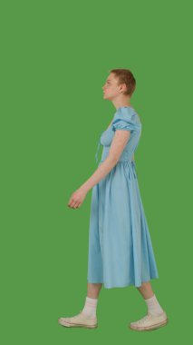 Mavi elbiseli biri yeşil ekranda yürüyor, kroma anahtarı. Yan görünüm