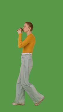 Sarı bluz giyen, elinde fincan tutan, yeşil ekranda yürüyen, krom anahtarı olan biri. Yan görünüm