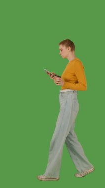 Bir insan yürür ve bir elinde akıllı telefon, diğer elinde bir bardak, yeşil ekranda ise krom anahtar kullanır. Yan görünüm