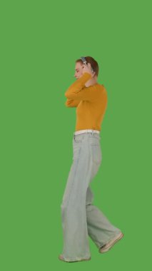 Kulaklık takan bir kişi yeşil ekranda dans ediyor ya da müzikten zevk alıyor, kroma tuşuyla. Yan görünüm, dikey video