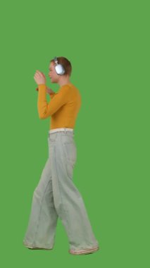 Kulaklık takan bir kişi yeşil ekranda dans ediyor ya da müzikten zevk alıyor, kroma tuşuyla. Yan görünüm, dikey video